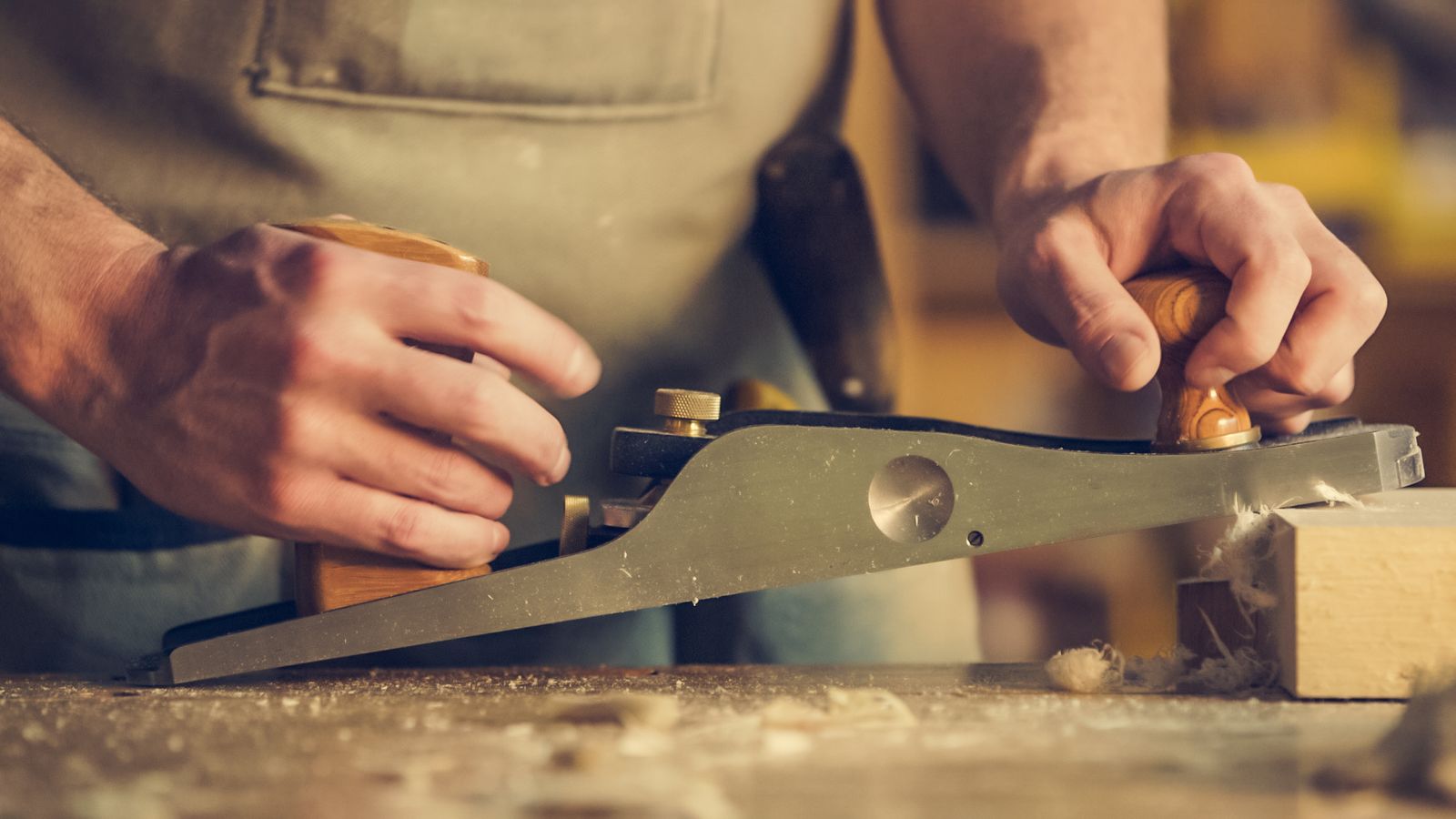 Handwerker bearbeitet ein Holzbrett mit einem Handhobel