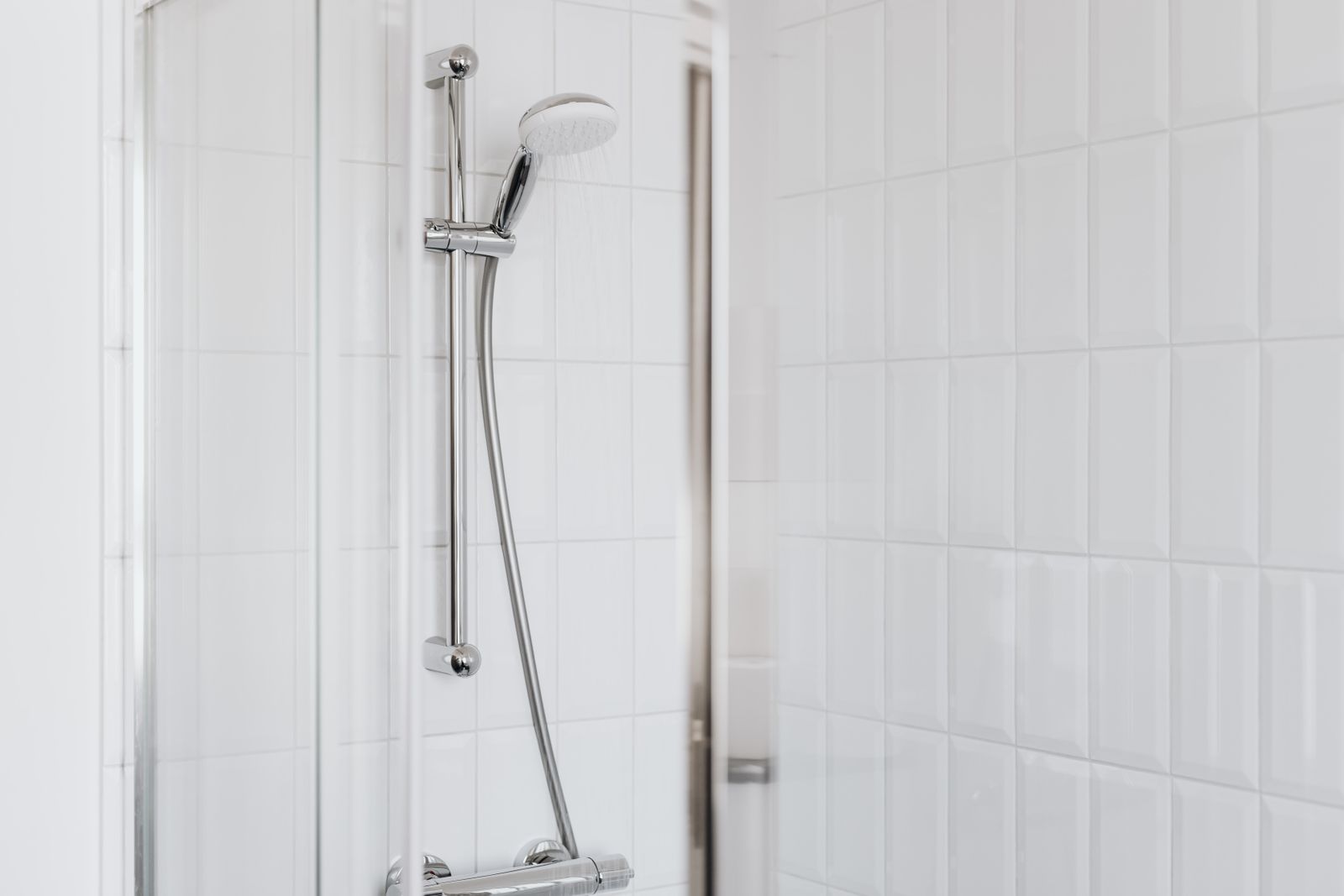 Dusche mit weißen Fliesen und Chrom-Armatur