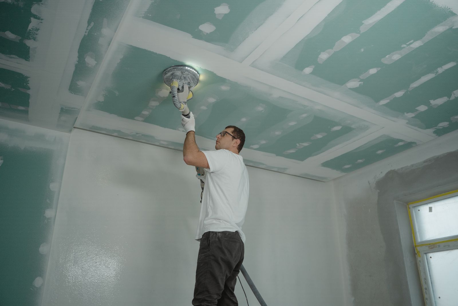 Handwerker arbeitet über Kopf an einer abgehängten Decke
