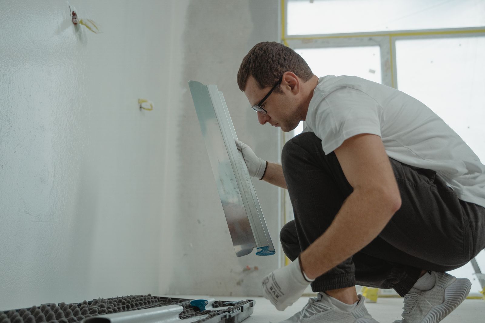 Handwerker verspachtelt mit einem Spachtel eine Wand im Innenausbau